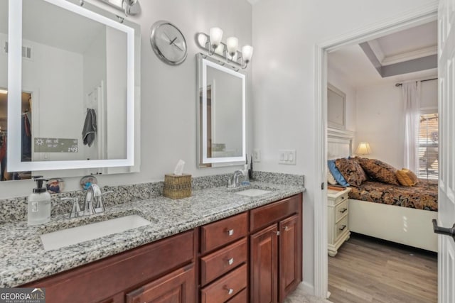 full bath featuring double vanity, a tray ceiling, a sink, and wood finished floors