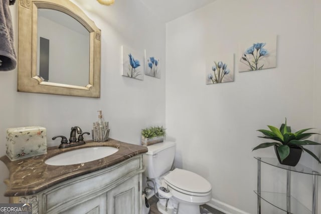 bathroom featuring toilet, vanity, and baseboards