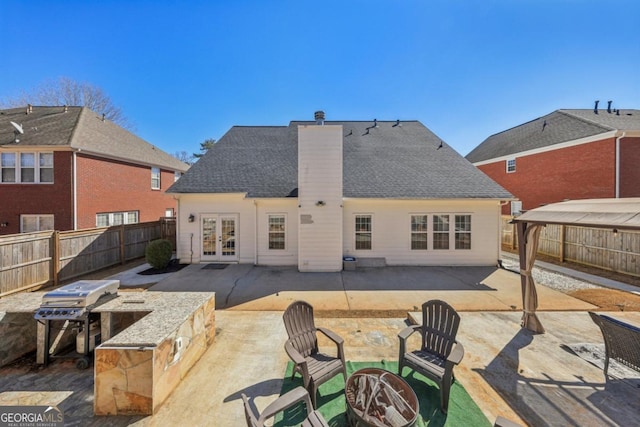 back of property with a patio area, a fenced backyard, a chimney, and french doors