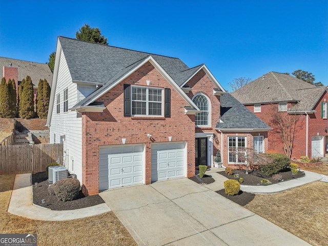 traditional home featuring an attached garage, brick siding, fence, driveway, and roof with shingles