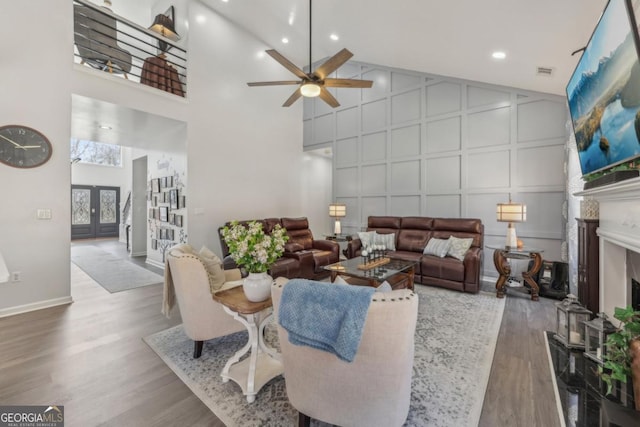 living area featuring high vaulted ceiling, a fireplace, a decorative wall, and wood finished floors