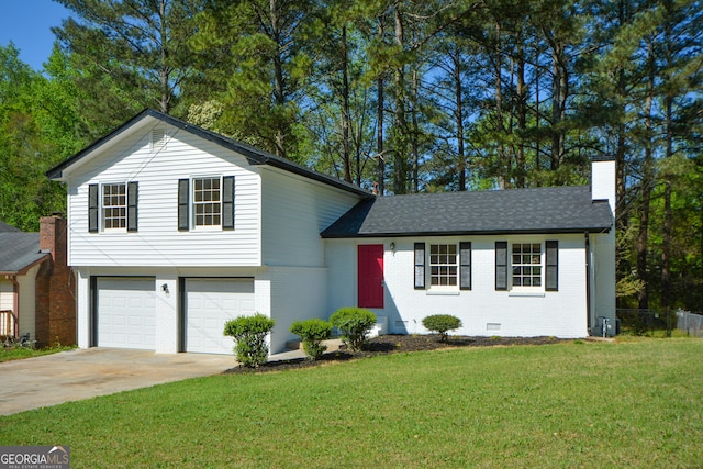 split level home with a garage, a front lawn, brick siding, a chimney, and driveway