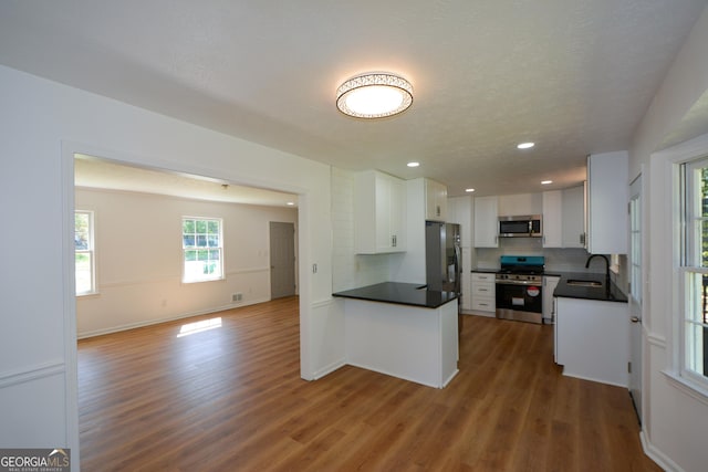 kitchen with tasteful backsplash, open floor plan, dark countertops, appliances with stainless steel finishes, and a sink