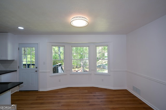 unfurnished dining area with recessed lighting, dark wood-style floors, baseboards, and visible vents
