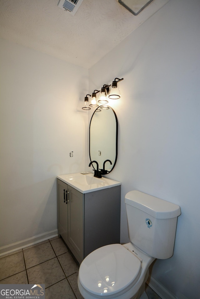 bathroom with vanity, baseboards, tile patterned flooring, toilet, and visible vents