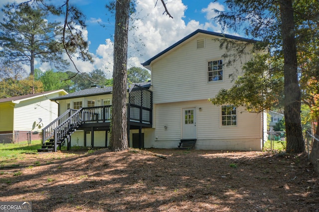 rear view of house featuring entry steps, fence, a deck, and stairway