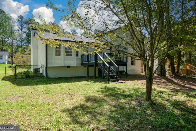 rear view of property with a deck, a yard, fence, and stairway