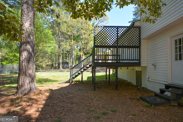 view of yard with stairway, entry steps, fence, a trampoline, and a deck