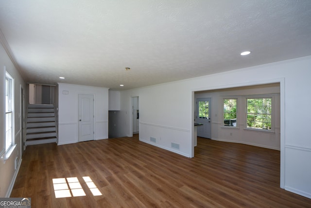 unfurnished living room featuring crown molding, wood finished floors, visible vents, and stairs