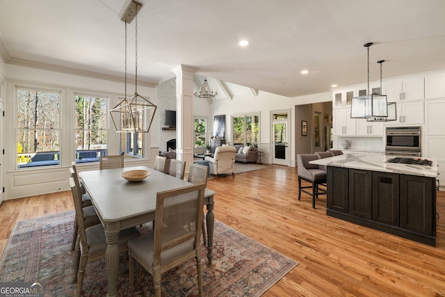 dining room with plenty of natural light, crown molding, light wood-style floors, and an inviting chandelier