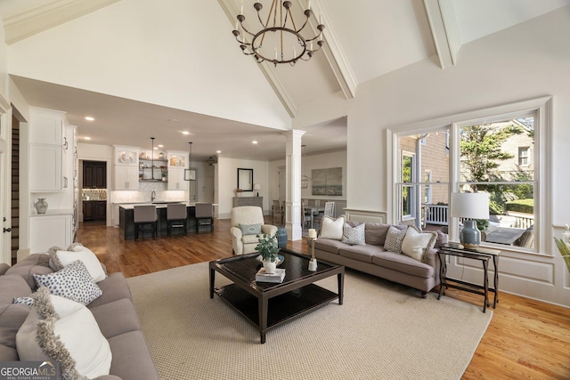 living area with beam ceiling, high vaulted ceiling, wood finished floors, and ornate columns