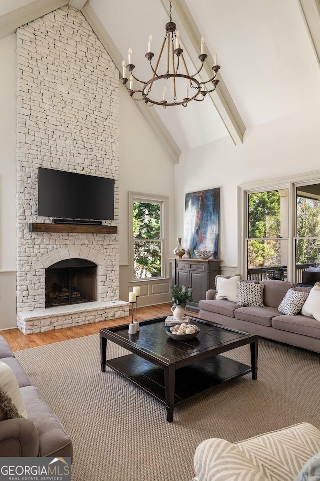 living room featuring beam ceiling, a fireplace, an inviting chandelier, wood finished floors, and high vaulted ceiling