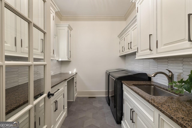 clothes washing area with baseboards, cabinet space, a sink, washer and dryer, and crown molding