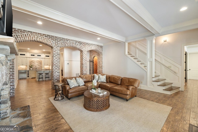 living area with beam ceiling, stairway, ornamental molding, and wood-type flooring