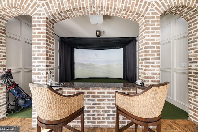 sitting room featuring golf simulator and brick wall