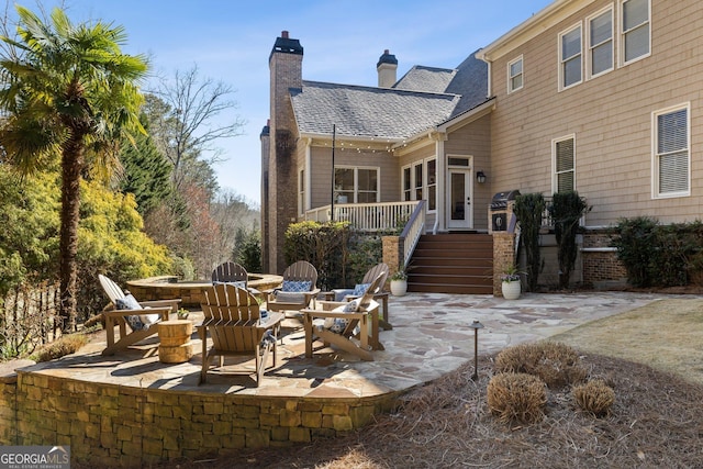 back of house with a patio area, stairway, a chimney, and a shingled roof