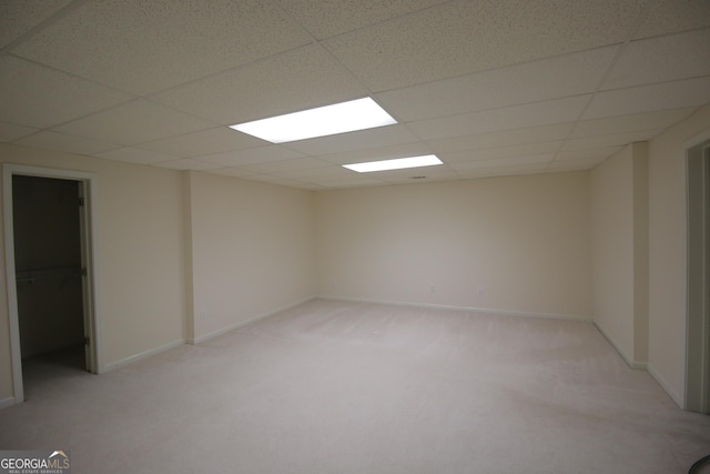 interior space with baseboards, a drop ceiling, and light colored carpet