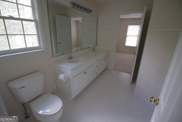 bathroom featuring toilet, double vanity, and a sink