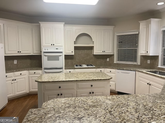 kitchen featuring light stone counters, white appliances, dark wood finished floors, and white cabinetry