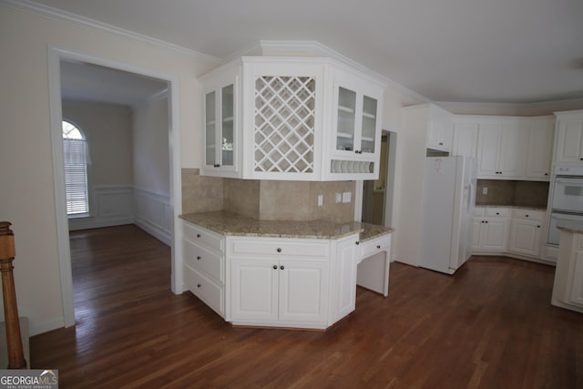 kitchen featuring dark wood finished floors, glass insert cabinets, ornamental molding, white cabinets, and white appliances