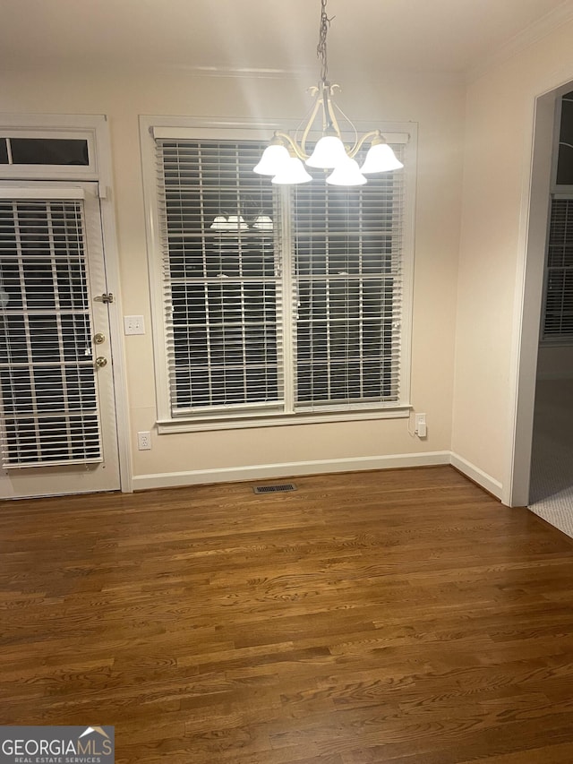 unfurnished dining area with a chandelier, visible vents, baseboards, and wood finished floors