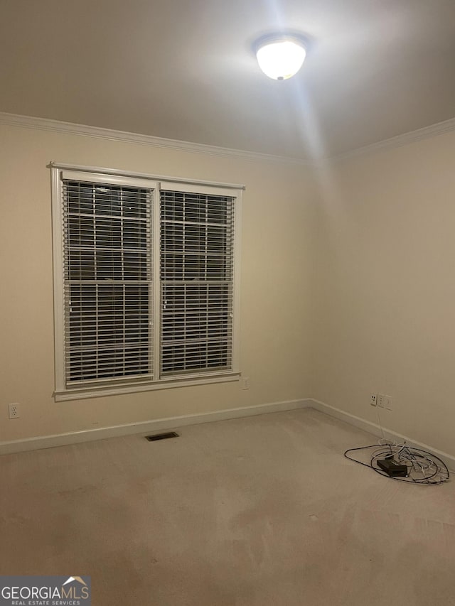 carpeted spare room with ornamental molding, visible vents, and baseboards