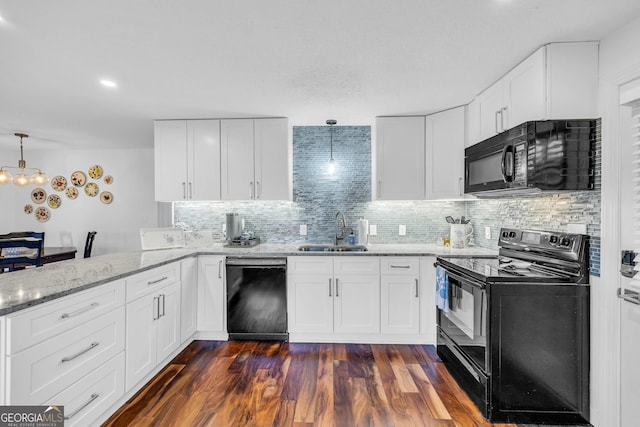 kitchen with light stone counters, tasteful backsplash, a sink, a peninsula, and black appliances