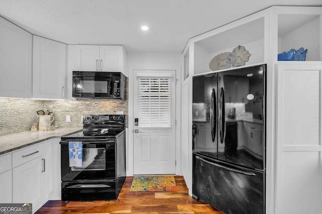 kitchen featuring dark wood-style floors, light stone countertops, black appliances, white cabinetry, and backsplash