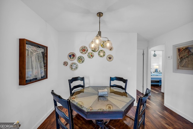 dining area featuring a notable chandelier, baseboards, and dark wood-style flooring