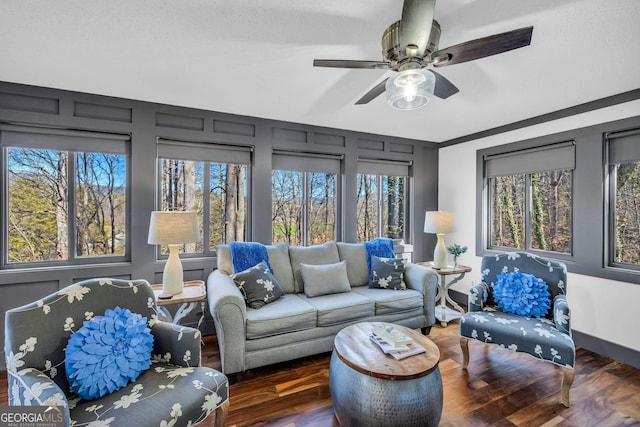 living area with baseboards, a ceiling fan, and wood finished floors