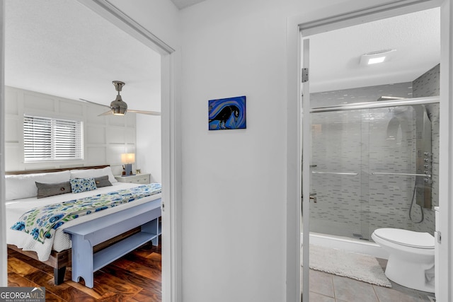 tiled bedroom with ceiling fan and a textured ceiling