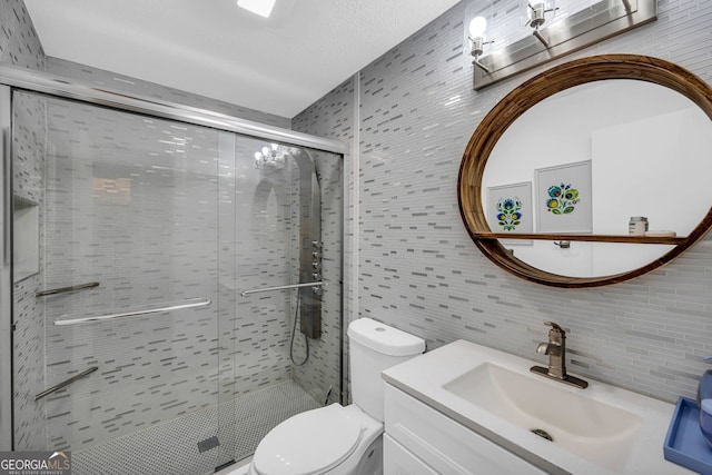 full bathroom with toilet, a shower stall, a textured ceiling, and vanity