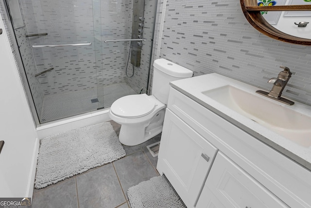 bathroom featuring tile walls, decorative backsplash, toilet, a stall shower, and vanity