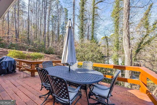 wooden terrace with a grill and outdoor dining area