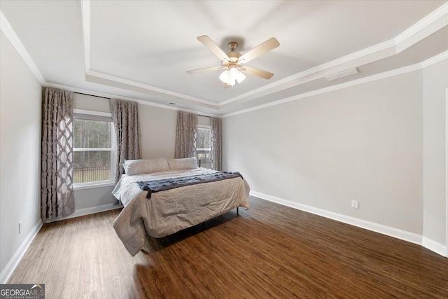 bedroom featuring crown molding, wood finished floors, a raised ceiling, and baseboards