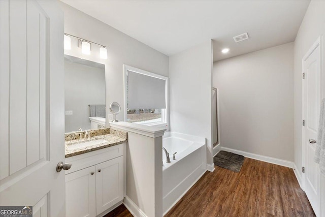 full bathroom featuring visible vents, vanity, wood finished floors, baseboards, and a bath