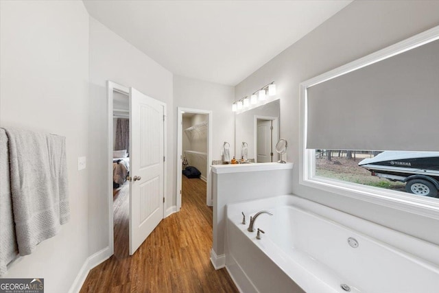 bathroom featuring a garden tub, baseboards, and wood finished floors