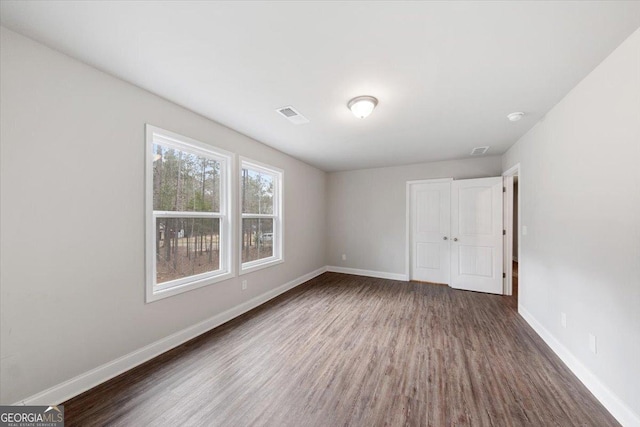 unfurnished bedroom featuring visible vents, baseboards, and wood finished floors