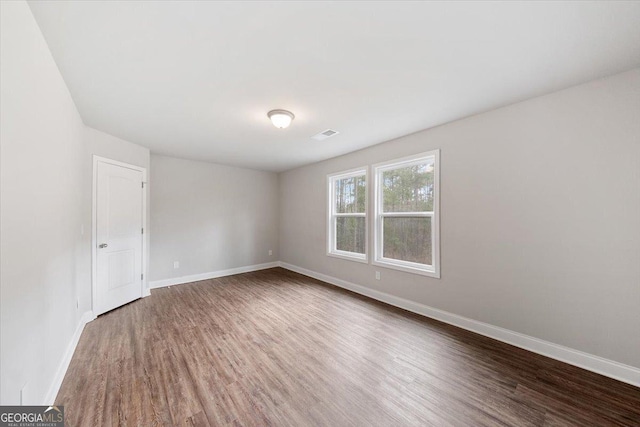 spare room featuring visible vents, baseboards, and wood finished floors