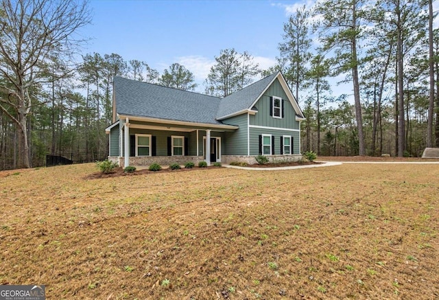 view of front facade featuring stone siding, a shingled roof, board and batten siding, and a front yard