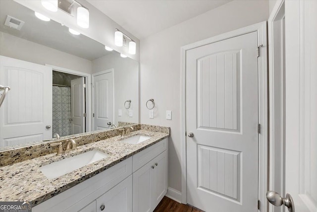 full bath with double vanity, walk in shower, a sink, and visible vents