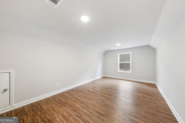 additional living space featuring lofted ceiling, visible vents, baseboards, and wood finished floors