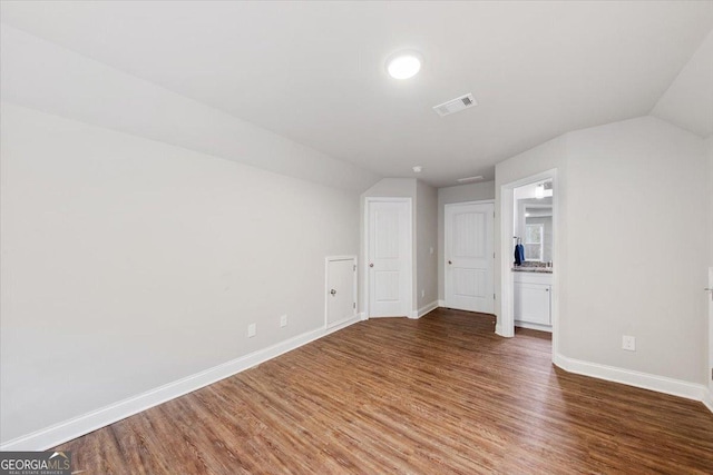 interior space featuring visible vents, vaulted ceiling, and wood finished floors