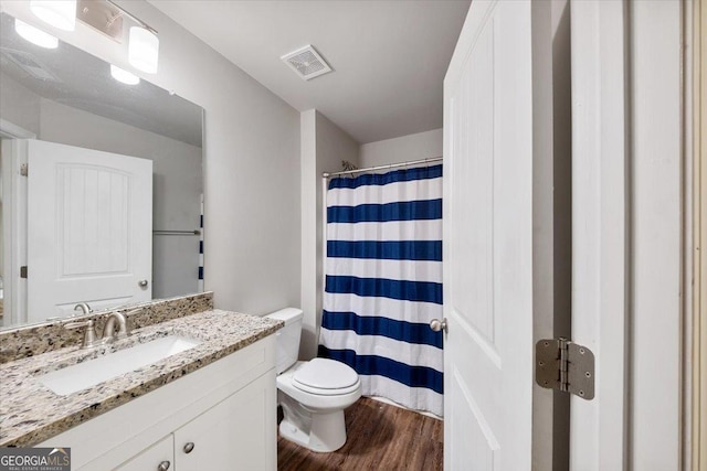 bathroom featuring visible vents, toilet, wood finished floors, curtained shower, and vanity