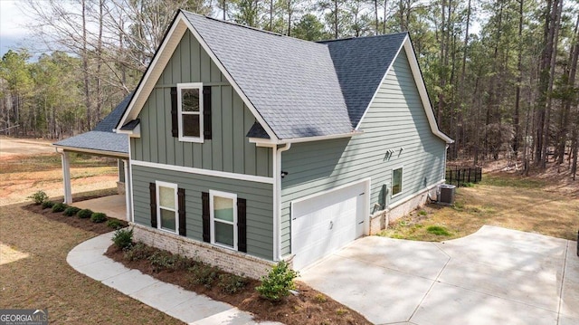 view of front of home featuring a garage, central AC, brick siding, a shingled roof, and board and batten siding