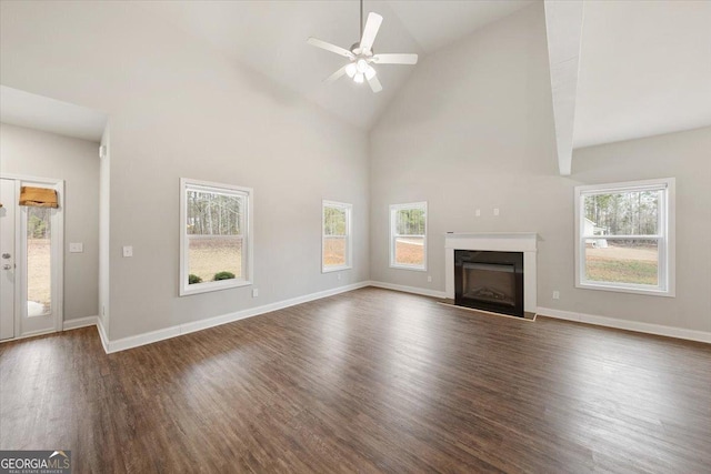 unfurnished living room with dark wood finished floors, a fireplace, plenty of natural light, and baseboards