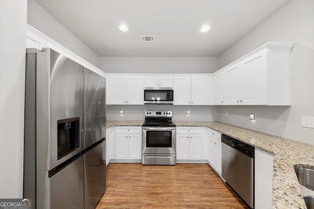 kitchen with light wood-style floors, appliances with stainless steel finishes, and white cabinets