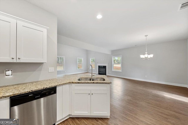 kitchen with open floor plan, a peninsula, stainless steel dishwasher, white cabinetry, and a sink