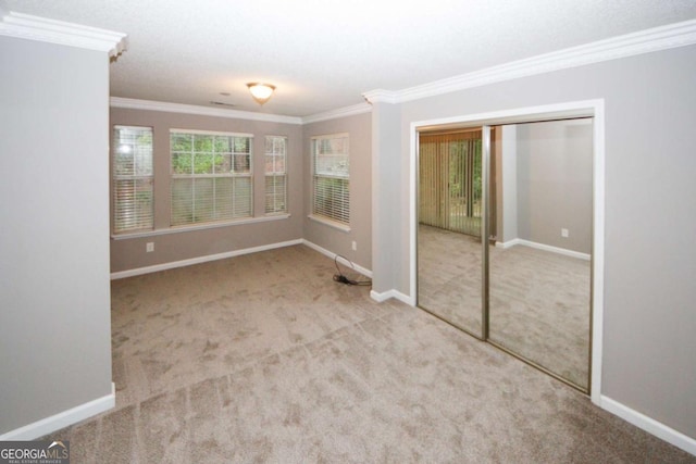 interior space with carpet floors, baseboards, ceiling fan, and ornamental molding