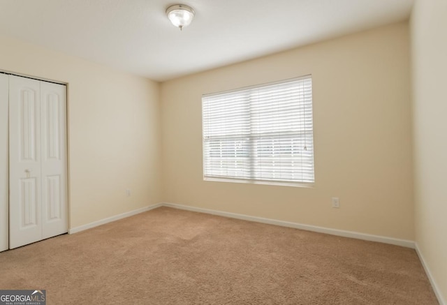 unfurnished bedroom featuring carpet, baseboards, and a closet